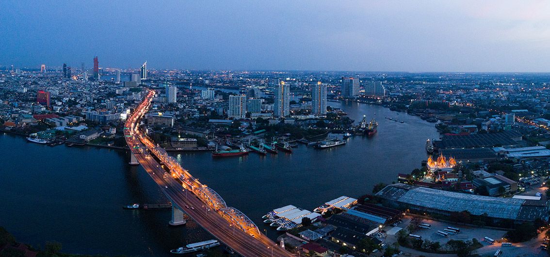 Abendlich beleuchtete Ufersilhouette Bangkoks, Thailand